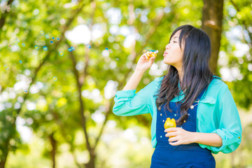 Young beautiful asian girl blowing bubbles outdoors.