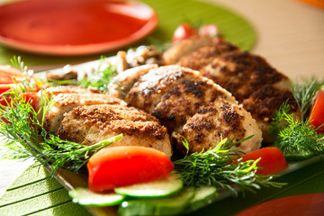 Breading chicken cutlets on a plate with dill tomatoes and cucum