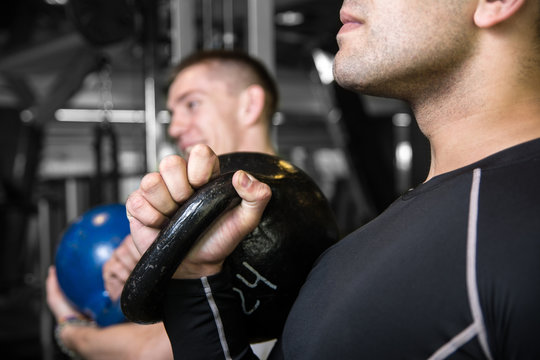 Close-up Kettlebell Swing Training Of Two Young Men In The Gym.