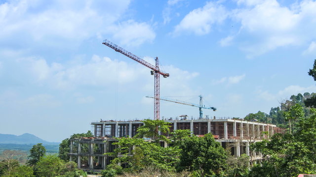 Building construction cranes working under sunlight sky.