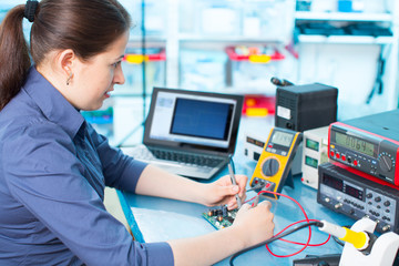 Woman with a tester and a printed circuit board