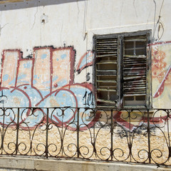 Graffiti painted around window shutters of a derelict house