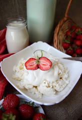 Dish of cottage cheese with sour cream and strawberries.
