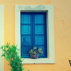 Fototapeta na wymiar Old house yellow wall with blue door and window. Greece Santorin