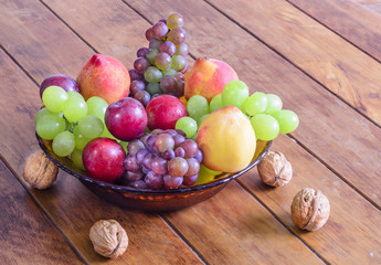 Bowl with fresh,healthy and delicious fruits, on wooden table.