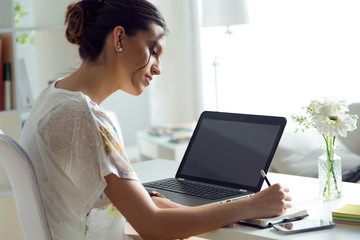 Pretty young woman using her laptop in the office.