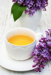 Obraz na płótnie Canvas Cup of tea and lilac flowers
