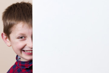 Smiling little boy with white blank placard, board,poster.