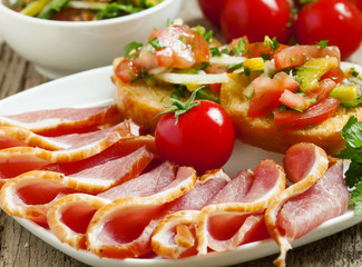 Pork smoked ham and tomatoes on the board, selective focus