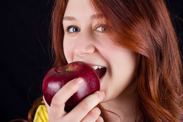 Young woman smiling and eating a fresh red apple