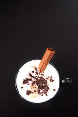 Cappuccino with chocolate on a black background. top view