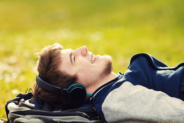 Student relaxing lying on grass and listening to music.