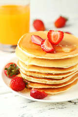 Delicious pancakes with strawberry on white wooden background