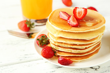 Delicious pancakes with strawberry on white wooden background