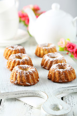Bundt cakes on cutting board on white wooden background