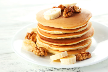 Delicious pancakes with banana on white wooden background