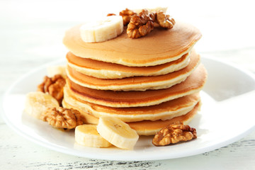 Delicious pancakes with banana on white wooden background