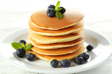 Delicious pancakes with blueberries on white wooden background