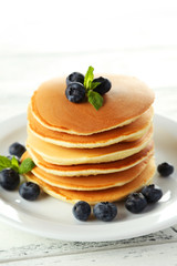 Delicious pancakes with blueberries on white wooden background