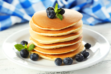 Delicious pancakes with blueberries on white wooden background