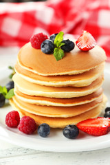Delicious pancakes with berries on white wooden background