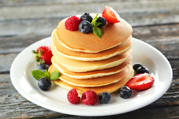 Delicious pancakes with berries on blue wooden background