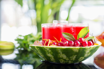 Set of glasses with alcohol cocktail with cranberry juice on a table in a restaurant with a creative composition of ice watermelon and fresh cranberries. soft focus