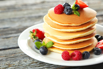 Delicious pancakes with berries on blue wooden background