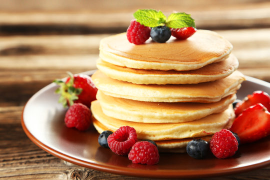 Delicious pancakes with berries on brown wooden background