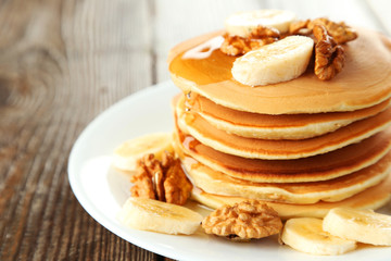 Delicious pancakes with banana on brown wooden background