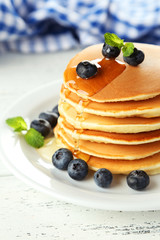Delicious pancakes with blueberries on white wooden background