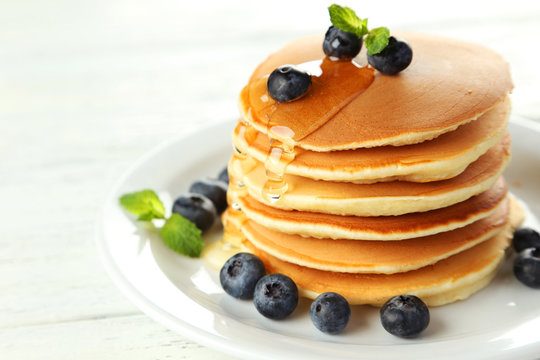 Delicious pancakes with blueberries on white wooden background
