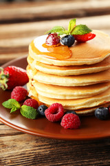 Delicious pancakes with berries on brown wooden background