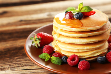 Delicious pancakes with berries on brown wooden background