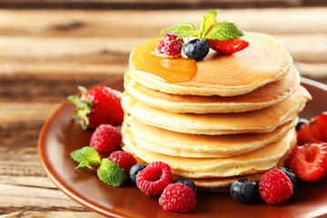 Delicious pancakes with berries on brown wooden background