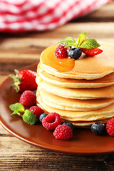 Delicious pancakes with berries on brown wooden background