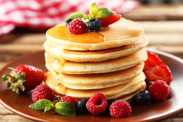 Delicious pancakes with berries on brown wooden background