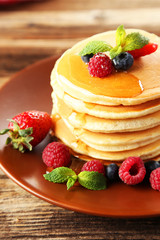 Delicious pancakes with berries on brown wooden background