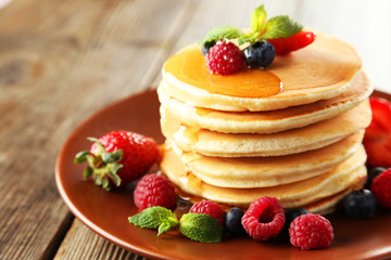 Delicious pancakes with berries on brown wooden background
