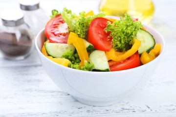 Fresh vegetable salad on white wooden background