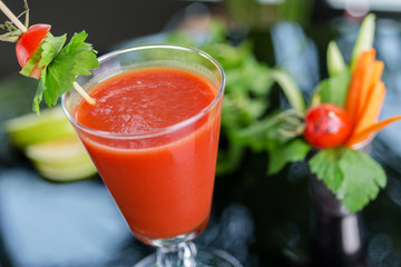 bright summer refreshing alcoholic cocktail Bloody Mary on a table in a restaurant with a creative decoration of cherry pepper greens. soft focus