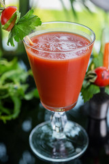 bright summer refreshing alcoholic cocktail Bloody Mary on a table in a restaurant with a creative decoration of cherry pepper greens. soft focus