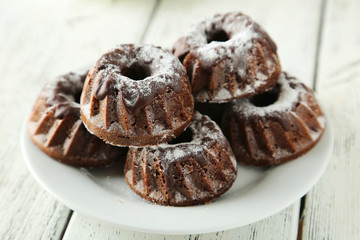 Chocolate bundt cakes on plate on white wooden background
