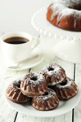 Chocolate bundt cakes on plate on white wooden background