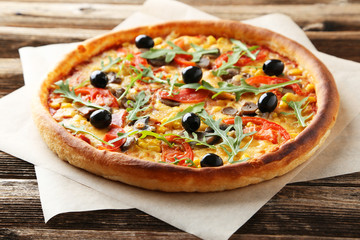 Fresh tasty pizza on brown wooden background