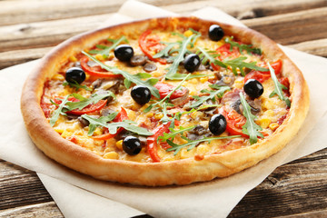 Fresh tasty pizza on brown wooden background