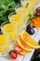 Set of several bright glasses with cold alcoholic cocktail with orange juice on a wooden table in a restaurant with ice and creative decoration of berries, fresh mint and orange slices. soft focus