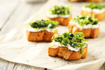 Tasty fresh bruschetta on parchment on grey wooden background