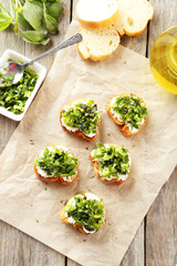 Tasty fresh bruschetta on parchment on grey wooden background