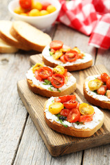 Tasty fresh bruschetta with tomatoes on cutting board on grey wo